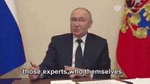 a man in a suit and tie is sitting at a desk and talking about experts who themselves