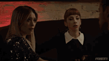 a woman in a sequined dress is sitting next to another woman in a black sweater ..