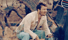a man is sitting on a tree trunk with unicornships written on the bottom