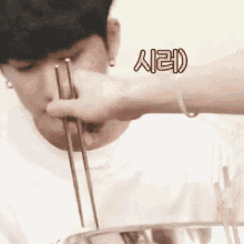 a man is eating noodles with chopsticks while wearing a bracelet .