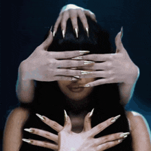 a woman with long nails covering her eyes with her hands