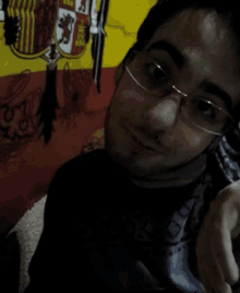 a man wearing glasses takes a selfie in front of a flag