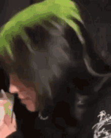 a close up of a person with green hair and a black shirt .