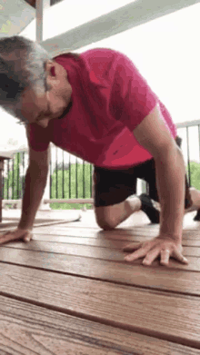 a man in a pink shirt is doing push ups on a deck .