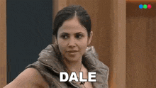 a woman in a vest says dale in front of a wooden wall