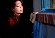 a woman looking out a window with her hands folded