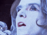 a close up of a woman 's face singing into a silver microphone