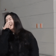 a woman is laughing with her hand on her face .