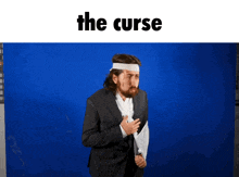 a man in a suit with a bandage on his head is standing in front of a blue background with the curse written on it