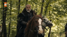 a man is riding a horse through a forest .