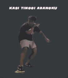 a man is dancing in front of a pink and purple star with the words kasi tinggi abangku written on it .
