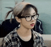 the girl is wearing glasses and a plaid shirt .