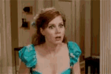 a woman in a blue dress is standing in front of a mirror .