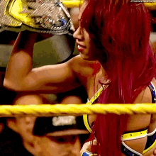 a woman with red hair is in a wrestling ring holding a championship trophy .