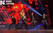 a group of men are dancing on a stage in front of a crowd .