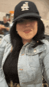 a woman wearing a la hat and denim jacket