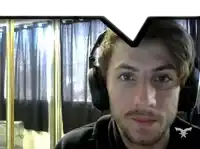 a man wearing headphones looks at the camera and has a x on his shirt