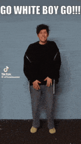 a man is standing in front of a blue wall and says go white boy go !!