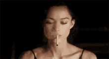 a woman is smoking a cigarette in a dark room in a close up of her face .