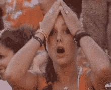 a woman covering her head with her hands while watching a game