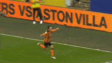a soccer player runs on the field in front of a sign that says ston villa