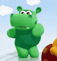 a green stuffed animal is standing in front of a cloudy sky