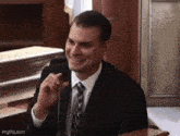 a man in a suit and tie is smiling in front of a microphone ..