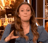 a woman in a blue polka dot shirt is making a funny face while talking on a television show .