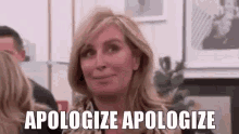 a woman is sitting in a room with a group of people and says `` apologize apologize '' .