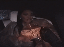a woman is sitting in the back seat of a car with a cigarette in her mouth .