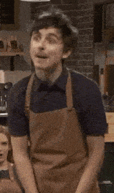 a man in a brown apron is dancing in a kitchen .