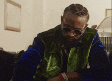 a man wearing sunglasses and a green jacket looks down