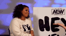 a woman is sitting in front of a sign that says aew wrestling