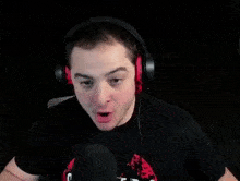 a man wearing headphones is sitting in front of a microphone and making a funny face .