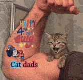 a cat is sitting on a man 's arm with a happy 4th of july tattoo on his arm