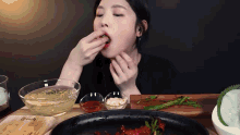 a woman is sitting at a table eating food from a bowl and a pan
