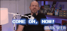 a man in front of a microphone with the words come on now dark web