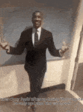 a man in a suit and tie is standing with his arms outstretched in a room