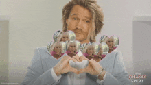 a man is making a heart shape with his hands with a freakier friday advertisement behind him