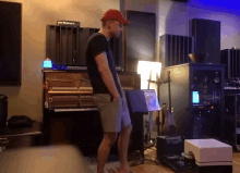 a man in a red hat is standing in a room with a piano
