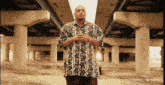 a man in a striped shirt stands under a bridge with haikuo ai written on the bottom