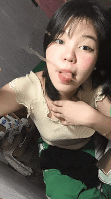 a woman with her tongue hanging out is wearing a white shirt and green shorts