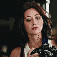 a woman is holding a camera and looking at the camera