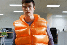 a man wearing an orange vest stands in a room