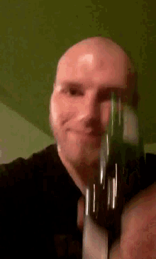 a bald man is holding a bottle in his hand