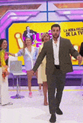 a man in a suit stands in front of a sign that says la hora feliz de la tv