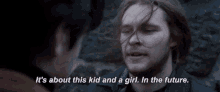 a man with long hair is talking to another man in a dark room .