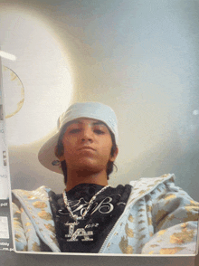 a young man wearing a hat and a necklace with the letter b on it