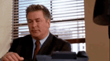 a man in a suit and tie sits at a desk
