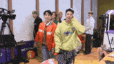 a group of young men are standing in a room with a sign that says idc radio on it